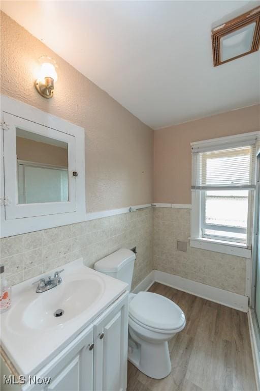 1222 W 6th St, Lorain, OH 44052 - bathroom with wood finished floors, toilet, vanity, wainscoting, and tile walls