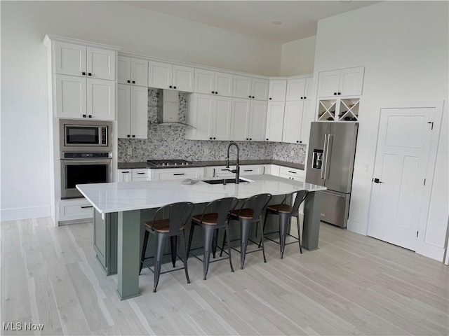 5771 E Blvd NW, Canton, OH 44718 - kitchen with appliances with stainless steel finishes, wall chimney range hood, light wood-type flooring, tasteful backsplash, and white cabinets