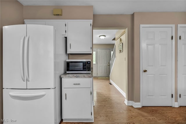 3895 Mars Dr, Brunswick, OH 44212 - kitchen featuring freestanding refrigerator, stainless steel microwave, light wood finished floors, white cabinets, and baseboards