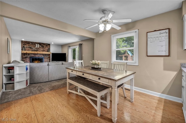 3895 Mars Dr, Brunswick, OH 44212 - dining space with light wood-type flooring, baseboards, ceiling fan, and a brick fireplace