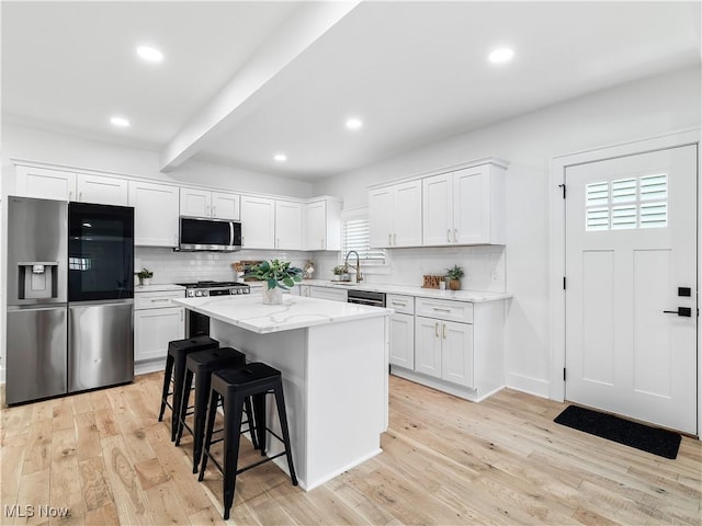 2295 Thurman Ave, Cleveland, OH 44113 - kitchen featuring stainless steel appliances, light wood-style floors, decorative backsplash, white cabinets, and recessed lighting