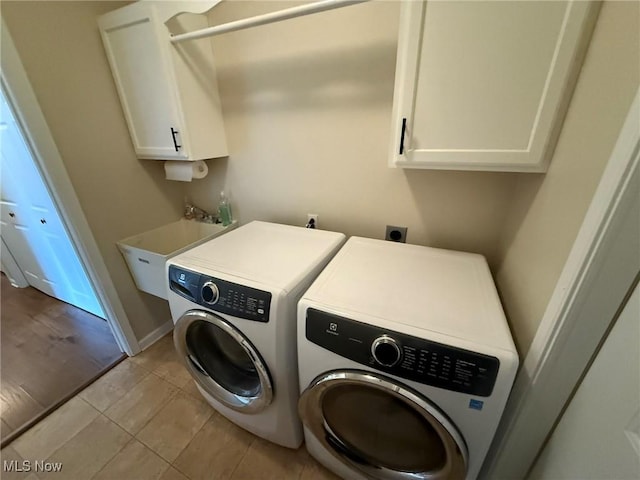 5645 Clingan Rd Unit 2D, Struthers, OH 44471 - laundry room featuring washing machine and dryer, cabinet space, light tile patterned flooring, and baseboards