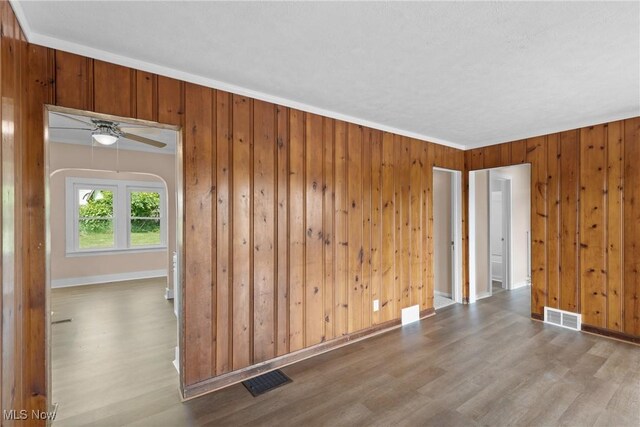 159 Locust St, Wintersville, OH 43953 - empty room featuring wood finished floors, wooden walls, baseboards, a ceiling fan, and arched walkways