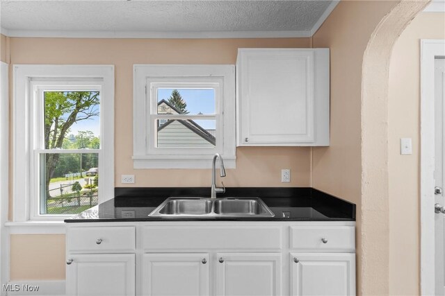 159 Locust St, Wintersville, OH 43953 - kitchen with a sink, dark countertops, white cabinets, a textured ceiling, and arched walkways