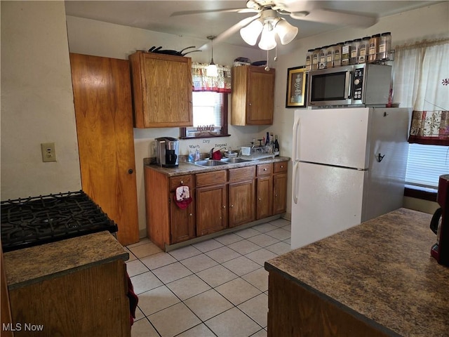 22061 Miller Ave, Euclid, OH 44119 - kitchen featuring stainless steel microwave, a sink, freestanding refrigerator, and brown cabinetry