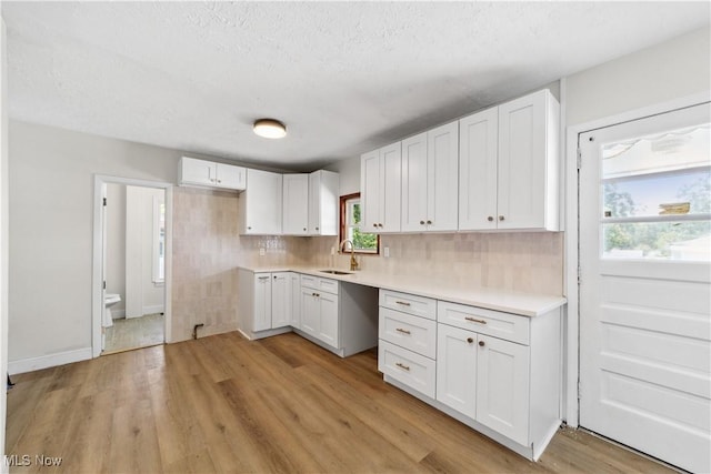 210 W 39th St, Lorain, OH 44052 - kitchen with a sink, white cabinets, light wood-style flooring, backsplash, and light countertops