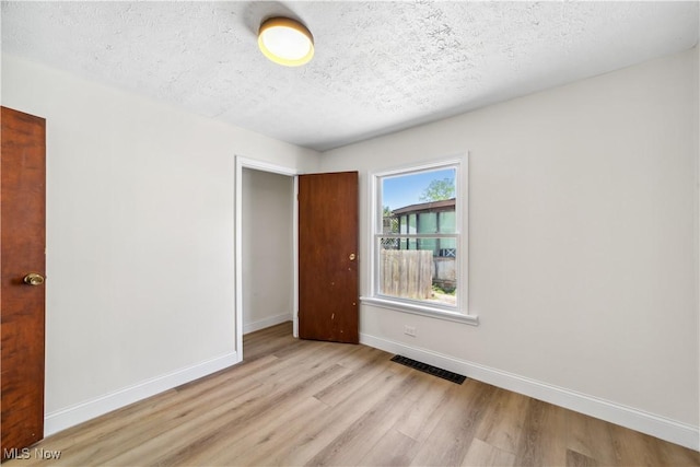 210 W 39th St, Lorain, OH 44052 - unfurnished bedroom featuring light wood-style floors, baseboards, and a textured ceiling