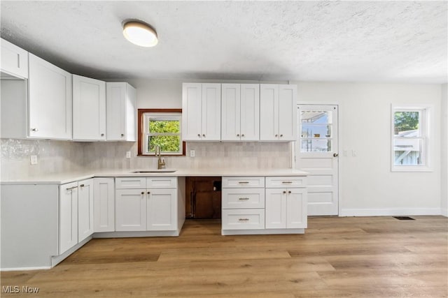 210 W 39th St, Lorain, OH 44052 - kitchen with a sink, white cabinetry, healthy amount of natural light, decorative backsplash, and a textured ceiling