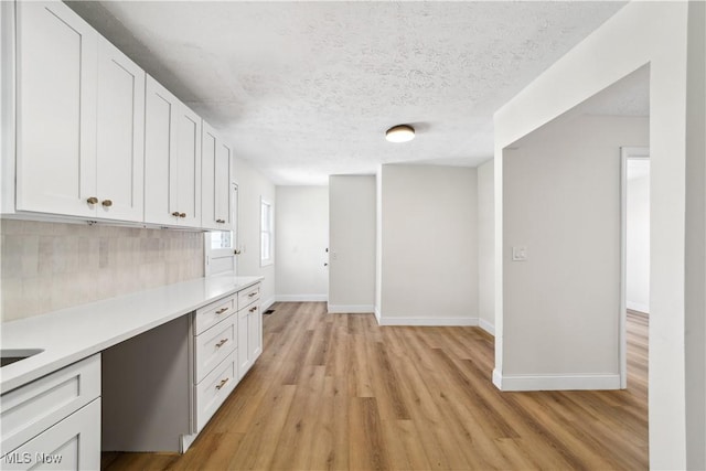 210 W 39th St, Lorain, OH 44052 - kitchen featuring light countertops, light wood-style flooring, white cabinetry, baseboards, and decorative backsplash