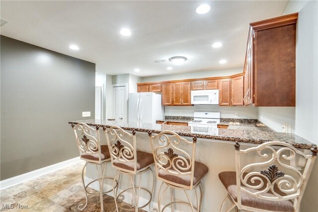 165 Woodbury Glen St, Hartville, OH 44632 - kitchen with white appliances, light stone counters, baseboards, recessed lighting, and a peninsula