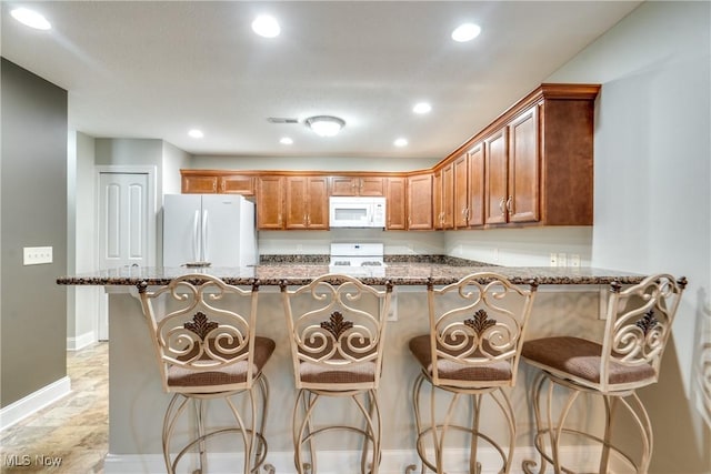 165 Woodbury Glen St, Hartville, OH 44632 - kitchen with white appliances, recessed lighting, dark stone counters, a breakfast bar, and baseboards