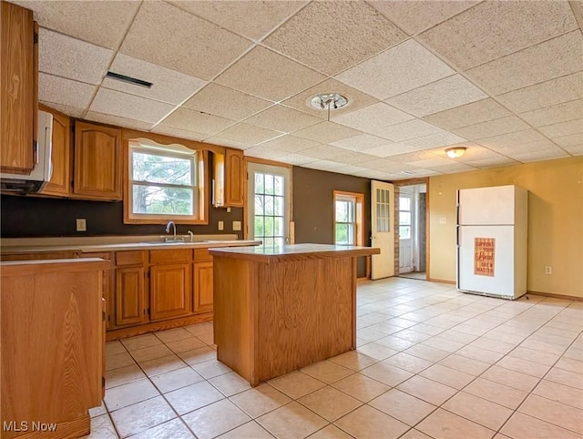 3189 Union Ave SE, Minerva, OH 44657 - kitchen featuring freestanding refrigerator, a center island, light tile patterned floors, a drop ceiling, and light countertops