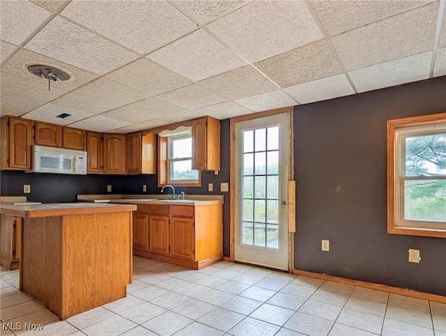 3189 Union Ave SE, Minerva, OH 44657 - kitchen featuring white microwave, a drop ceiling, light tile patterned floors, brown cabinetry, and baseboards