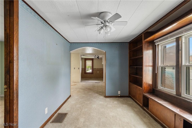 365 Stephens Rd, Akron, OH 44312 - empty room with arched walkways, a ceiling fan, baseboards, built in features, and light colored carpet
