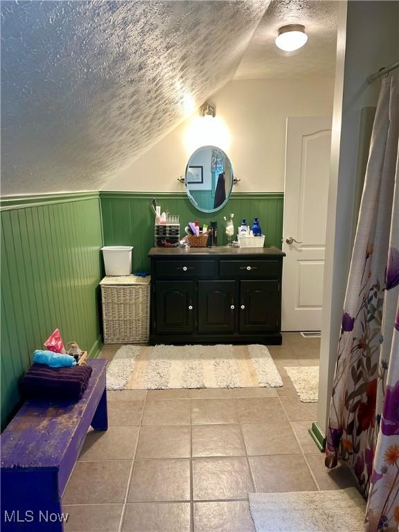 586 Columbia Rd, Valley City, OH 44280 - full bathroom with a textured ceiling, a wainscoted wall, vanity, vaulted ceiling, and tile patterned floors
