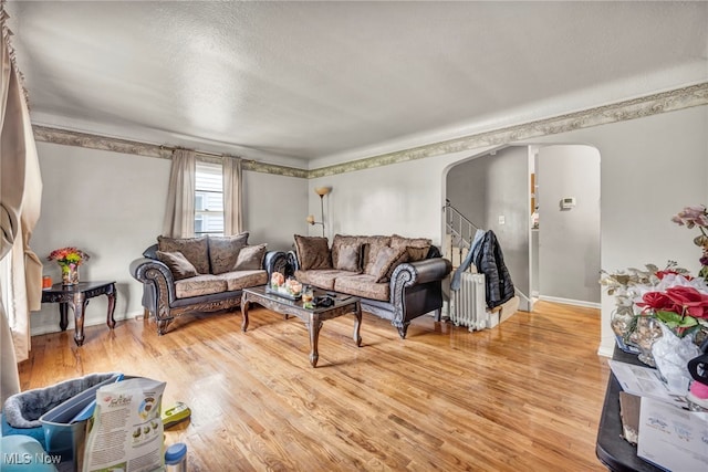 14901 Krems Ave, Maple Heights, OH 44137 - living room featuring arched walkways, light wood-style flooring, stairs, a textured ceiling, and baseboards