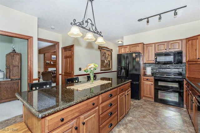4255 River Rd, Perry, OH 44081 - kitchen with black appliances, a kitchen island, pendant lighting, dark stone counters, and brown cabinetry