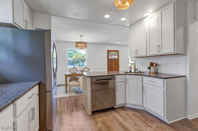 14148 Rochelle Dr, Maple Heights, OH 44137 - kitchen featuring stainless steel appliances, a peninsula, a sink, light wood-style floors, and decorative backsplash