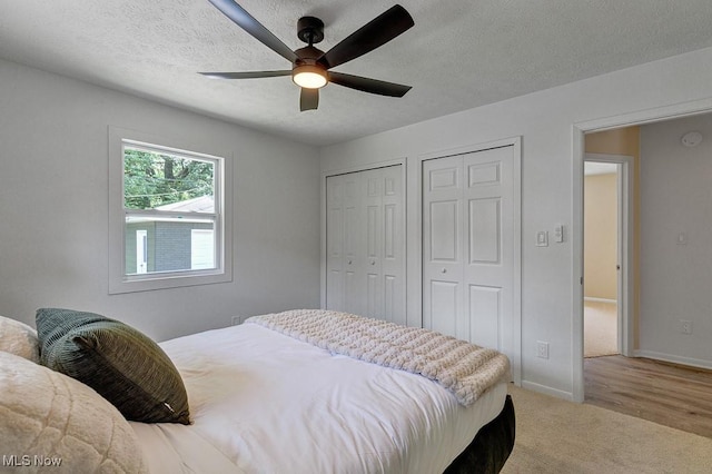 14148 Rochelle Dr, Maple Heights, OH 44137 - bedroom featuring two closets, baseboards, ceiling fan, a textured ceiling, and light colored carpet