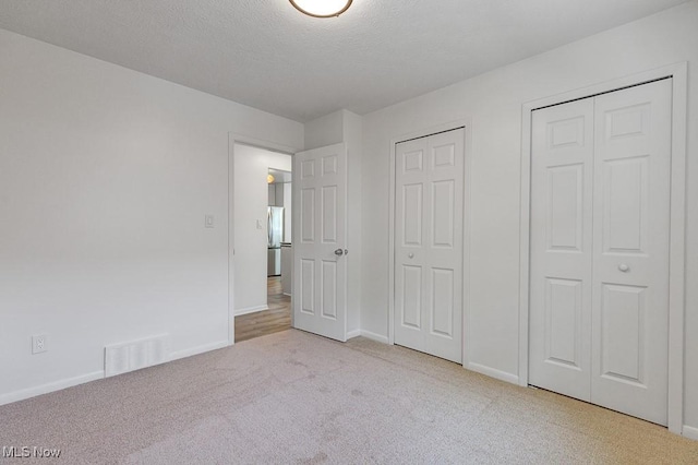 14148 Rochelle Dr, Maple Heights, OH 44137 - unfurnished bedroom with carpet floors, two closets, baseboards, freestanding refrigerator, and a textured ceiling