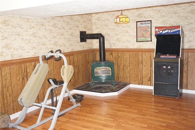 6019 New London Rd, Ashtabula, OH 44004 - detailed view of a wood stove, a wainscoted wall, wood finished floors, wallpapered walls, and wooden walls