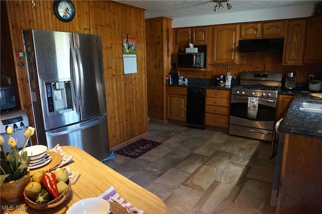 6019 New London Rd, Ashtabula, OH 44004 - kitchen with stainless steel appliances, wood walls, under cabinet range hood, brown cabinetry, and a sink