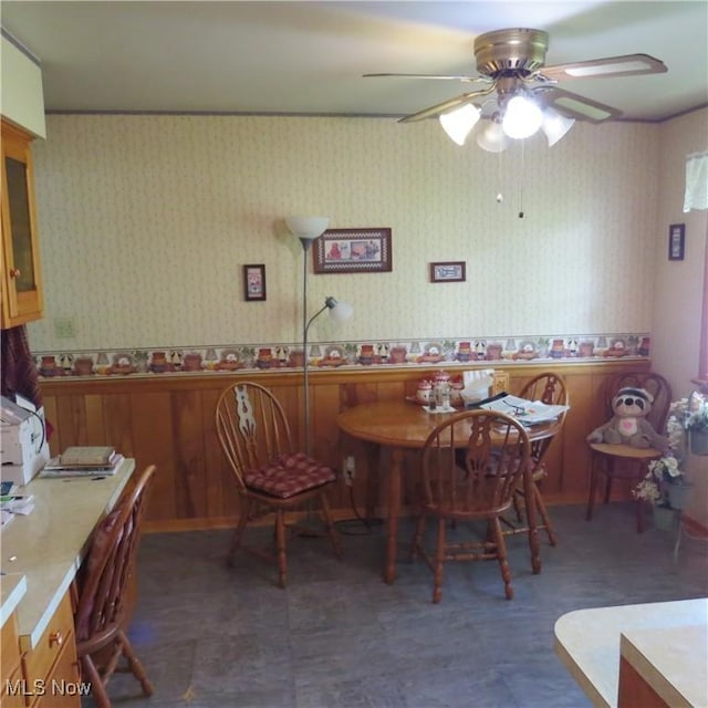 576 12th St NW, Carrollton, OH 44615 - dining space with wainscoting, wallpapered walls, a ceiling fan, and wood walls