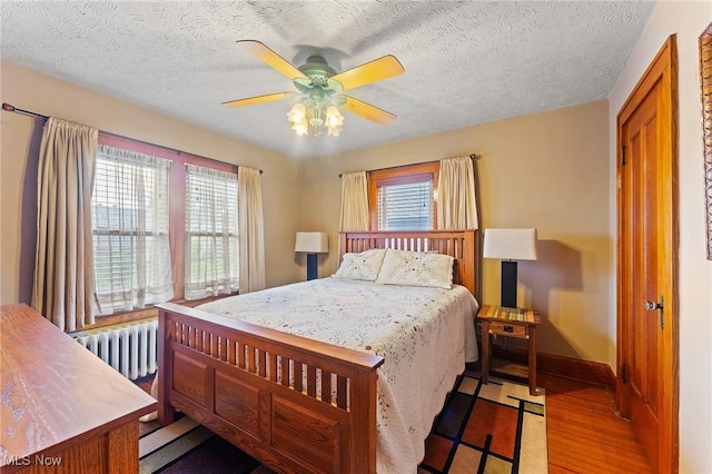 97 Overlook Blvd, Struthers, OH 44471 - bedroom with wood finished floors, radiator, a textured ceiling, baseboards, and ceiling fan