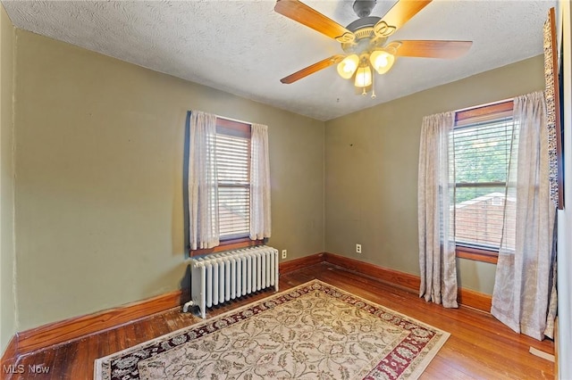 97 Overlook Blvd, Struthers, OH 44471 - empty room with radiator heating unit, wood finished floors, plenty of natural light, baseboards, and a textured ceiling