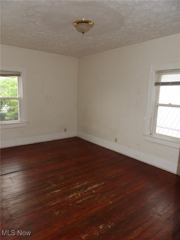 974 E Archwood Ave, Akron, OH 44306 - empty room featuring dark wood-type flooring, a textured ceiling, and baseboards