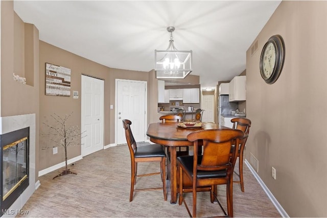 4044 Saint Andrews Ct, Canfield, OH 44406 - dining room with a chandelier, baseboards, light wood finished floors, and a glass covered fireplace