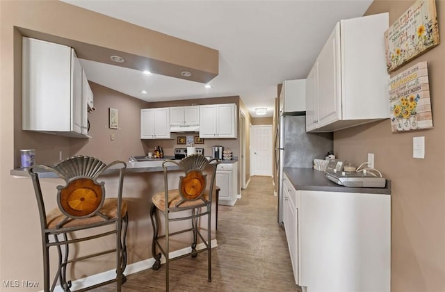 4044 Saint Andrews Ct, Canfield, OH 44406 - kitchen with a kitchen breakfast bar, under cabinet range hood, a peninsula, wood finished floors, and white cabinetry