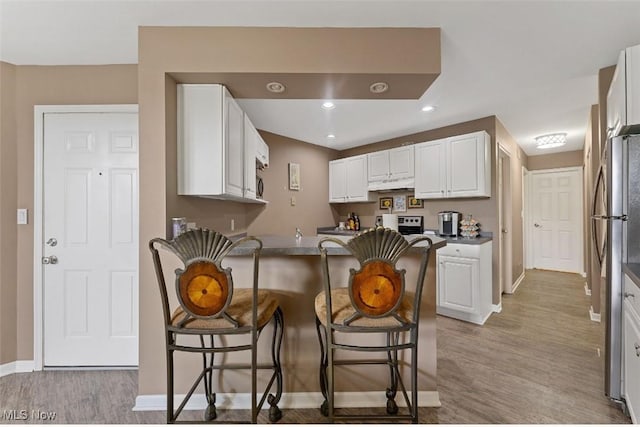 4044 Saint Andrews Ct, Canfield, OH 44406 - kitchen with baseboards, a peninsula, a breakfast bar, under cabinet range hood, and light wood-type flooring