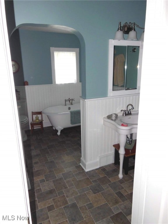 518 Hill St, Coshocton, OH 43812 - full bath featuring wainscoting, a freestanding bath, and stone finish floors