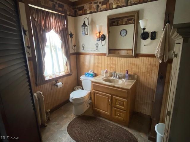 705 Main St, Toronto, OH 43964 - bathroom featuring radiator, wainscoting, vanity, toilet, and wooden walls