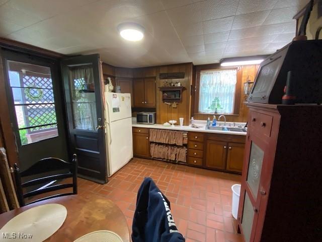 705 Main St, Toronto, OH 43964 - kitchen featuring stainless steel microwave, freestanding refrigerator, light countertops, brick patterned flooring, and a sink