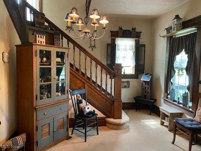 705 Main St, Toronto, OH 43964 - staircase featuring carpet flooring, a chandelier, and a textured ceiling