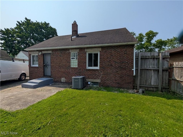 727 N Firestone Blvd, Akron, OH 44306 - back of house featuring central AC unit, a chimney, brick siding, and a shingled roof