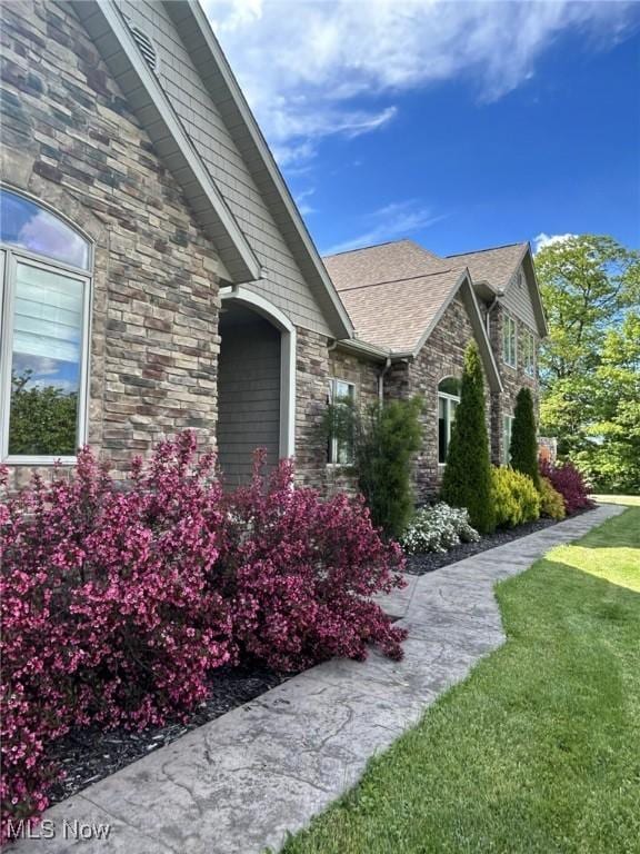 8320 Westfield Rd, Seville, OH 44273 - view of property exterior with stone siding, a lawn, and roof with shingles