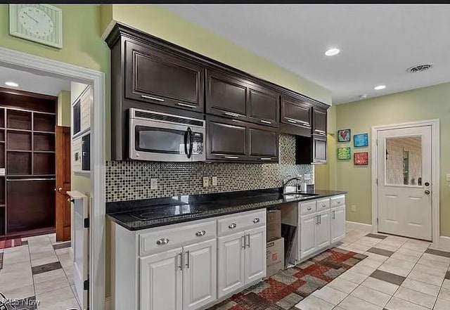8320 Westfield Rd, Seville, OH 44273 - kitchen with stainless steel microwave, light tile patterned flooring, decorative backsplash, a sink, and white cabinetry