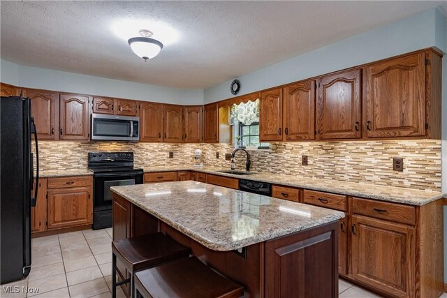 488 Maple Dr, Williamstown, WV 26187 - kitchen featuring black appliances, a sink, a center island, brown cabinets, and light stone counters