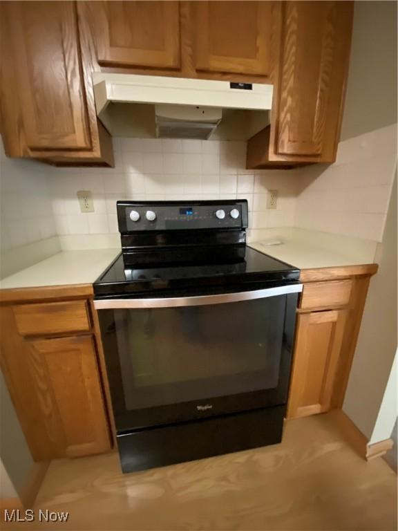 6234 W 54th St, Parma, OH 44129 - kitchen featuring black electric range oven, under cabinet range hood, light countertops, tasteful backsplash, and brown cabinets