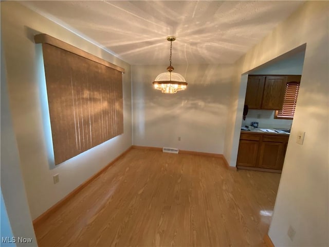 6234 W 54th St, Parma, OH 44129 - unfurnished dining area featuring light wood finished floors, a chandelier, and baseboards