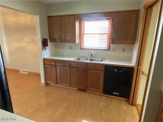 6234 W 54th St, Parma, OH 44129 - kitchen with a sink, dishwasher, brown cabinets, light wood-style floors, and light countertops