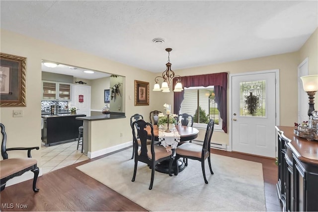 1421 Rolling Meadows Dr, Vermilion, OH 44089 - dining room featuring a chandelier, light wood-style floors, baseboard heating, and baseboards