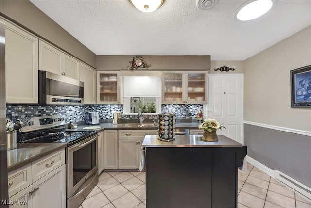 1421 Rolling Meadows Dr, Vermilion, OH 44089 - kitchen with stainless steel appliances, baseboard heating, tasteful backsplash, dark countertops, and a textured ceiling