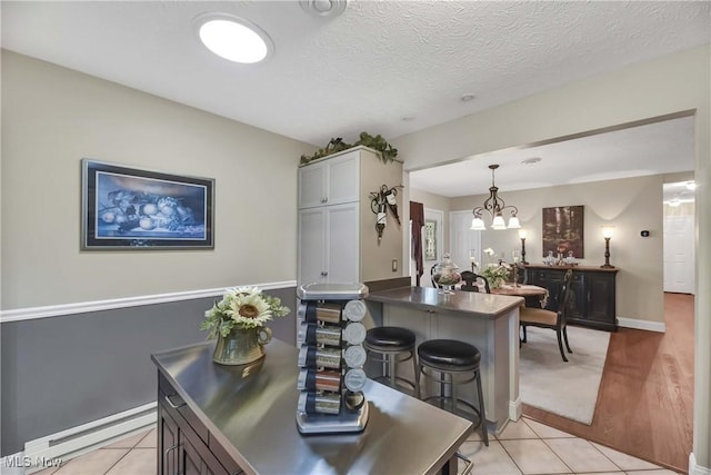 1421 Rolling Meadows Dr, Vermilion, OH 44089 - dining space with a baseboard heating unit, a chandelier, light tile patterned flooring, a textured ceiling, and baseboards