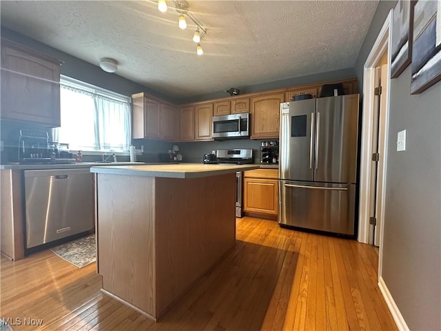 2280 Becket Cir, Stow, OH 44224 - kitchen featuring appliances with stainless steel finishes, a textured ceiling, light wood-style flooring, a center island, and light countertops