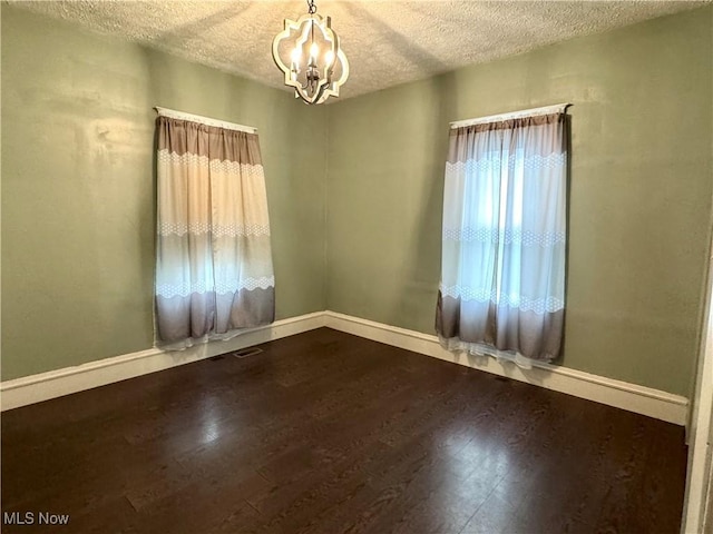 354 Hamilton Ave, Coshocton, OH 43812 - empty room featuring a chandelier, a textured ceiling, dark wood-style flooring, and baseboards