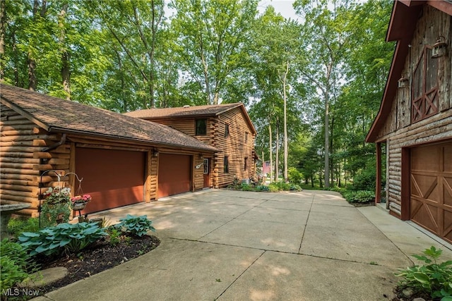 5820 Kildare Cir NW, Canton, OH 44718 - view of property exterior with log exterior, concrete driveway, a garage, and an outdoor structure
